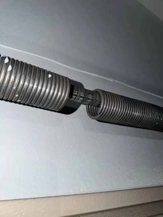 Close-up of a broken garage door torsion spring split at the break — spring repair diagnosis in Orange County, CA