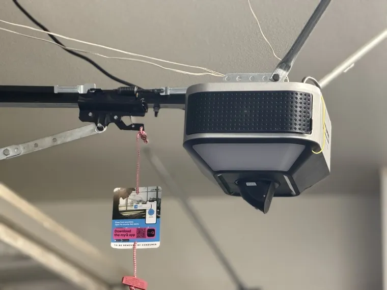 New myQ-ready garage door opener installed on a ceiling rail with its smart-control tag hanging beside it — smart opener installation in Orange County, CA