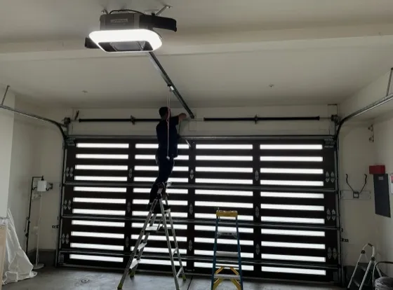 Technician on a ladder repairing the top rail and sections of a garage door — off-track garage door repair in Orange County