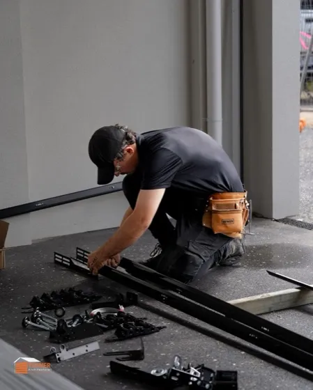 Technician assembling replacement garage door track and hardware on a driveway — same-day garage door repair in Laguna Hills, CA